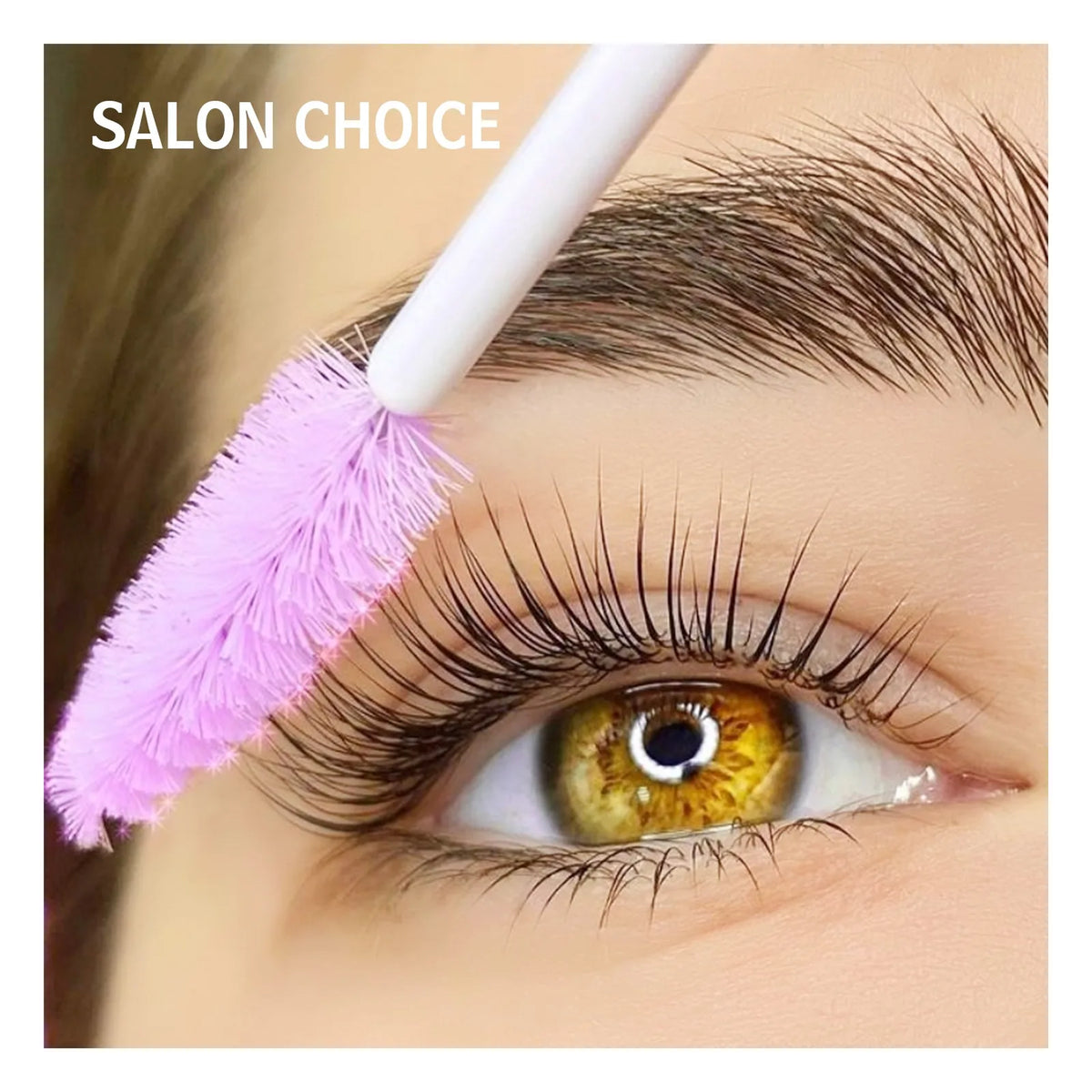 Close-up of lifted eyelashes and a pink spoolie brush grooming the eyebrow in a salon beauty image.