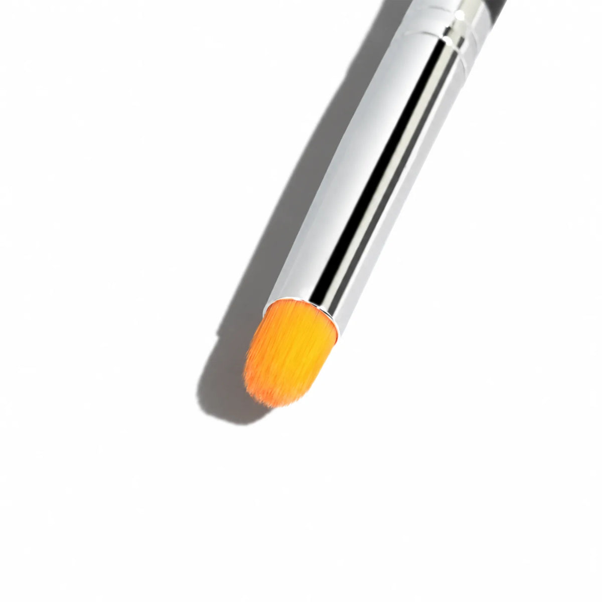 Close-up of short orange bristles and the silver ferrule on a Lomansa lash lift applicator brush.