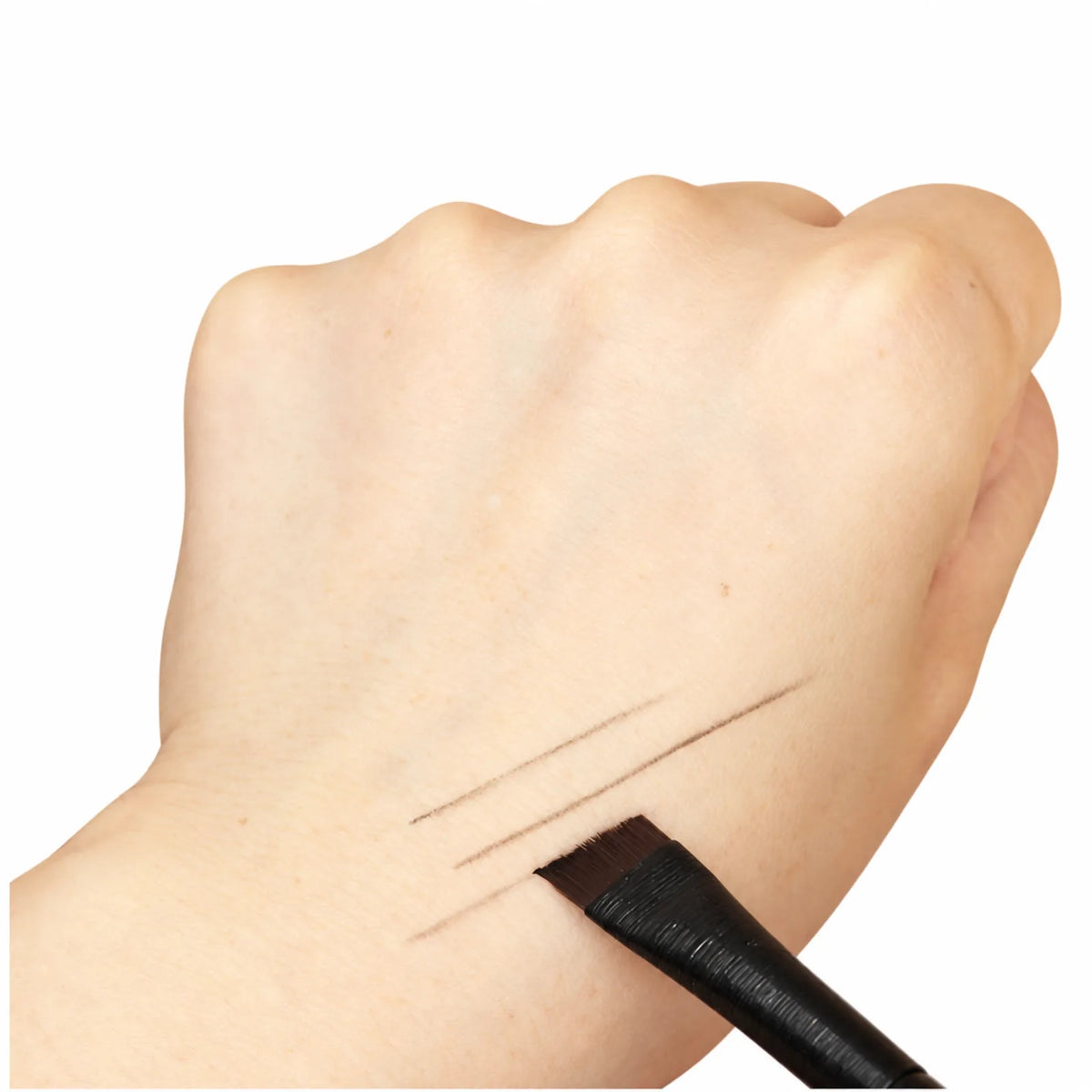 Lomansa black angled eyebrow brush testing fine brown makeup strokes on the back of a hand.
