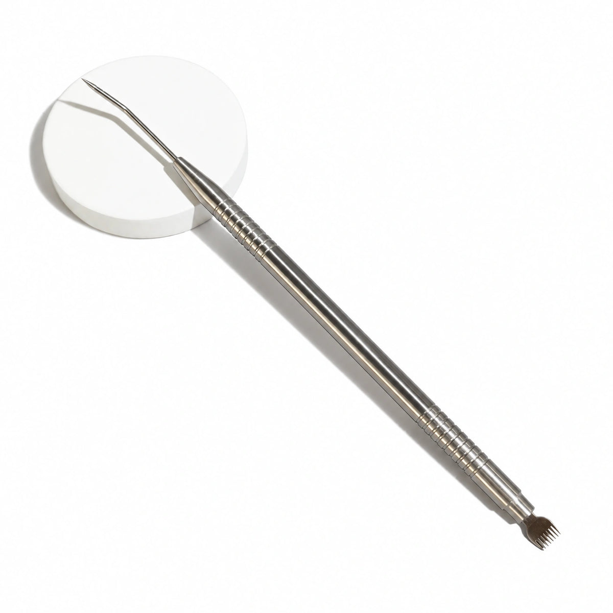 Lomansa silver dual-ended lash lift tool with an angled tip and comb end, displayed on a white round pedestal.