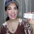 Woman holding two white Lomansa lash lifting adhesive boxes beside her face.